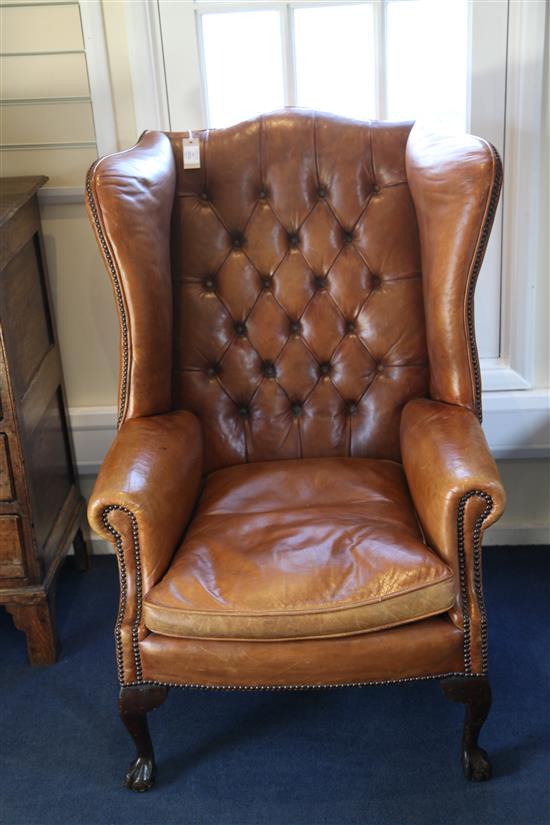 A pair of brown leather wingback armchairs,